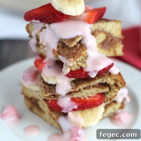 side view of three pieces of this french toast casserole, stacked with fresh strawberries and bananas