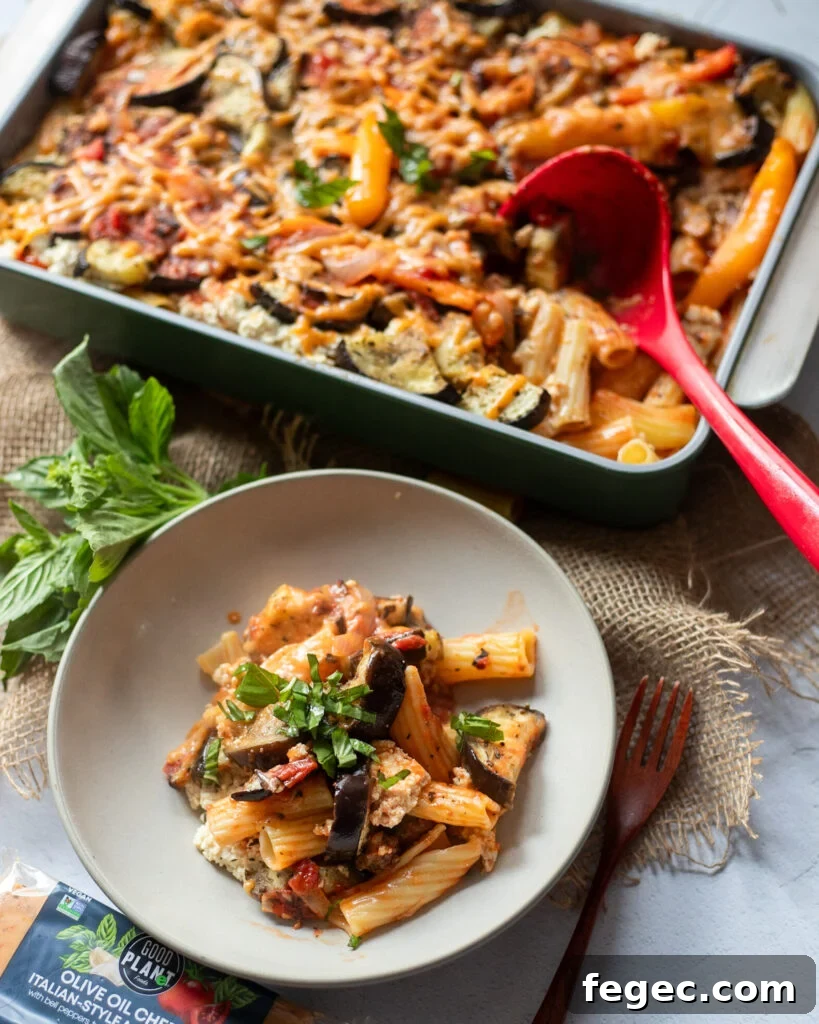 scooping vegan eggplant pasta out of a baking dish onto a plate and garnishing with fresh basil.