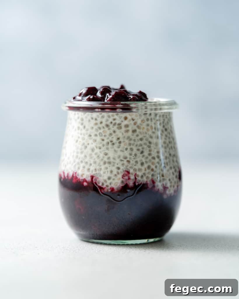 Glass jar with coconut chia pudding and blueberry sauce.