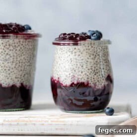 Side shot of a jar with blueberry jam at the bottom of the jar and chia pudding on the top layer topped with more blueberries.