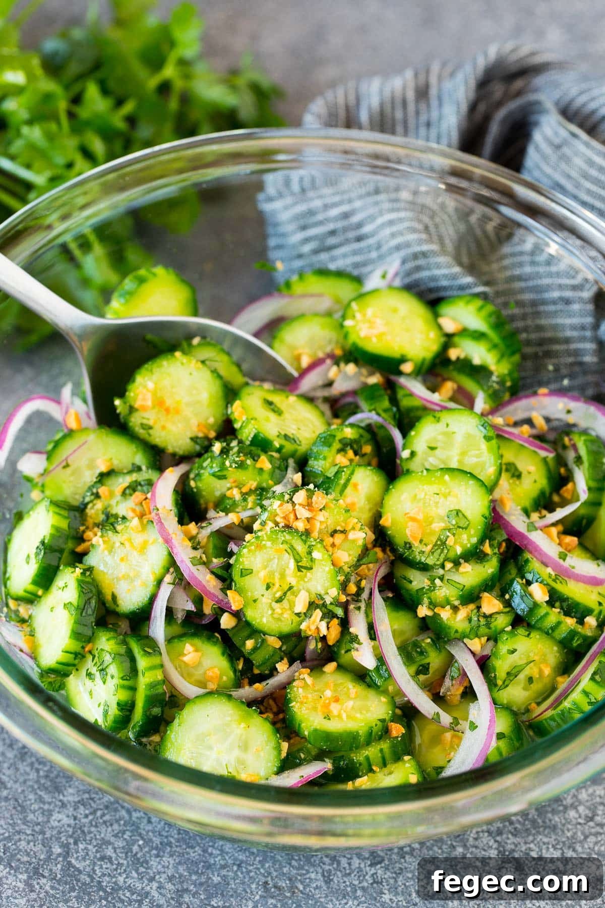 Thai cucumber salad in a bowl with a serving spoon.