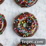 An aerial view of chocolate donuts with sprinkles on a marble table.