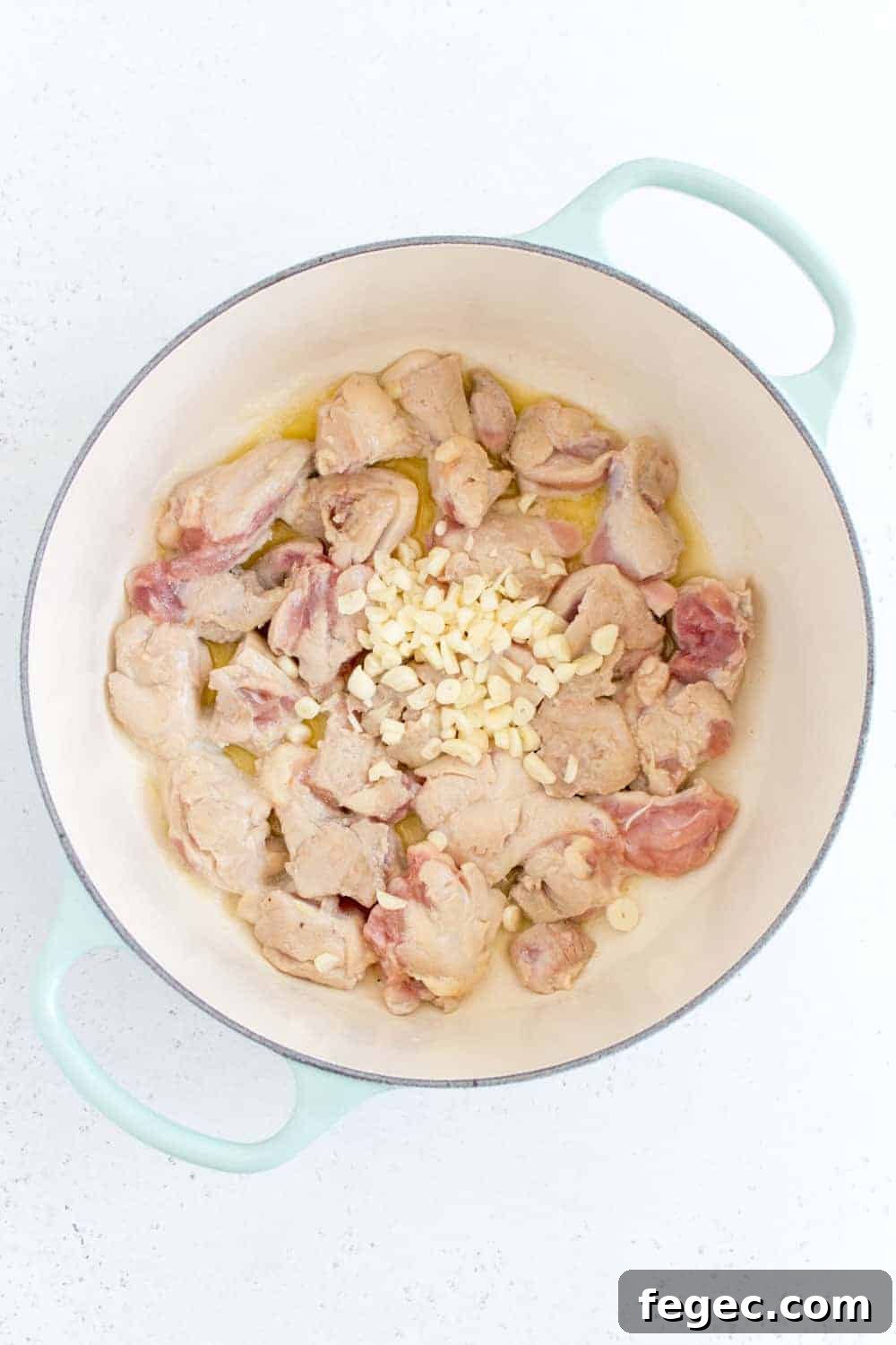 minced garlic added to chicken thighs in dutch oven