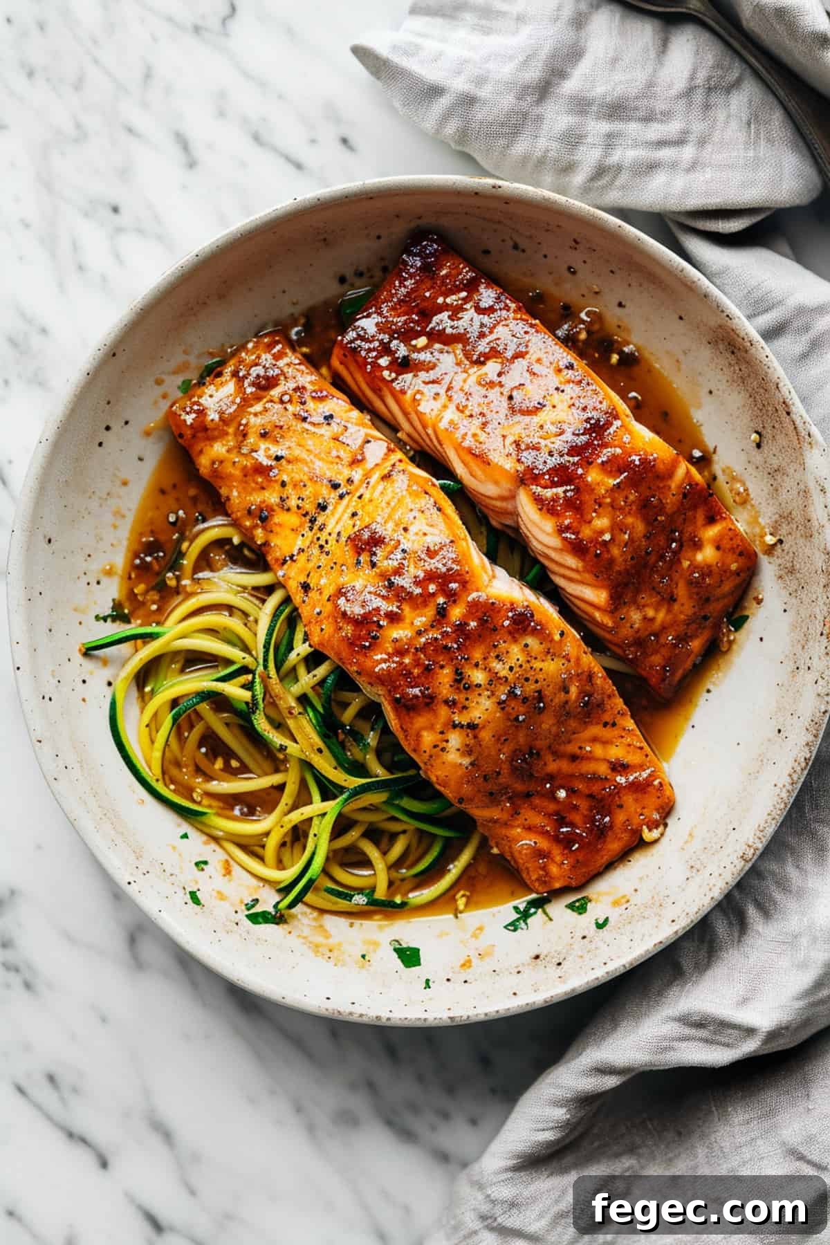 Maple glazed salmon in a pan with zucchini noodles.