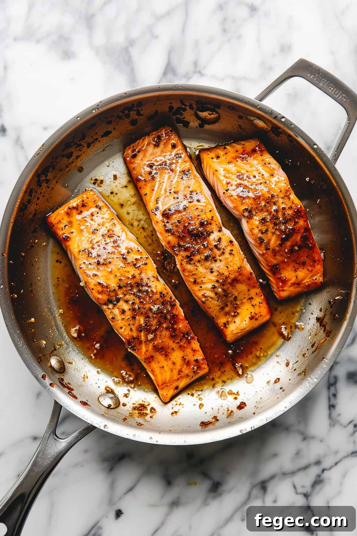 Maple glazed salmon in a pan with spices and sauce.