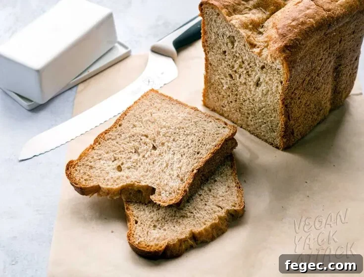 two slices of wheat bread next to the loaf and bread knife