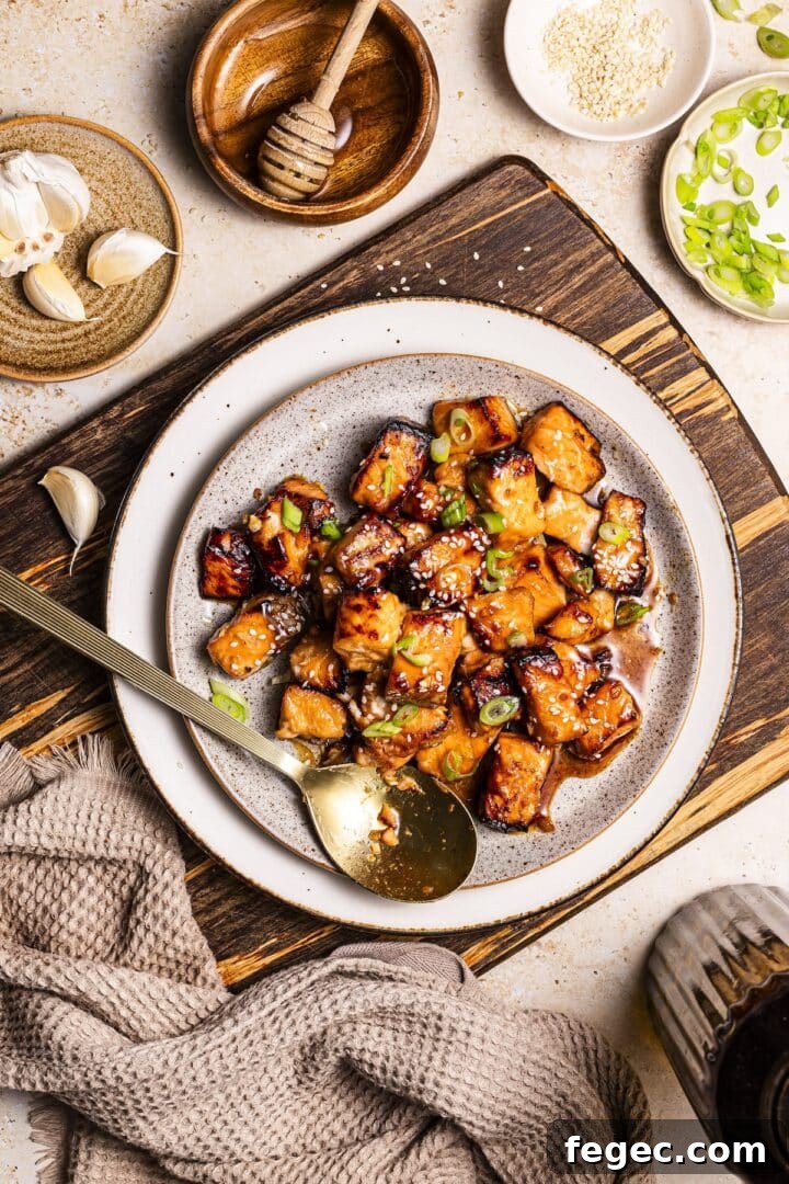 White bowl with air fryer salmon bites, topped with sliced green onion.