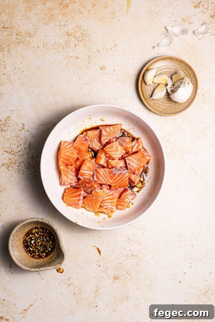 air fryer salmon bites in a medium white bowl with marinade.