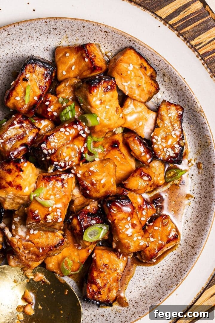 Air fryer salmon bites in a white speckled bowl, topped with thinly sliced green onion.