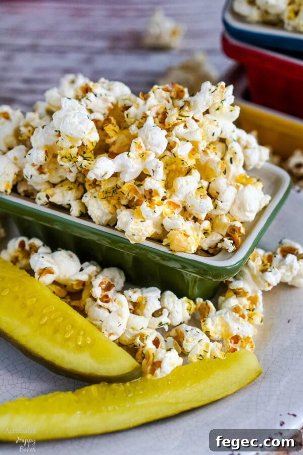 Dill pickles on a plate next to a bowl of dill pickle popcorn.