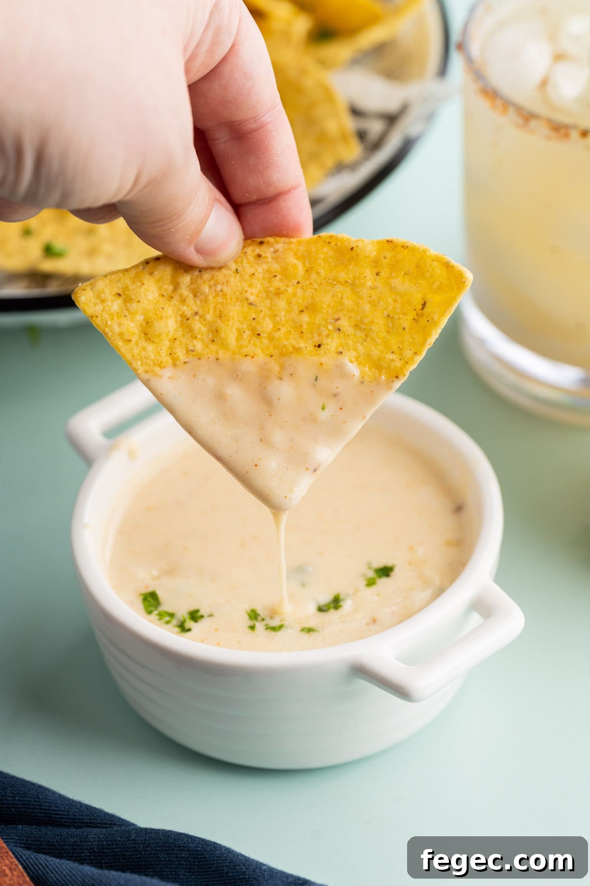 Tex-Mes queso blanco dripping off a tortilla chip