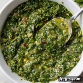 Green chimichurri sauce in a white bowl.