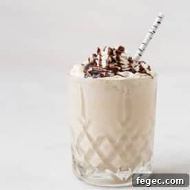 A glass of whiskey milkshake topped with whipped cream and chocolate syrup.