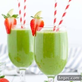 Two green drinks in stemmed glasses with paper straws.