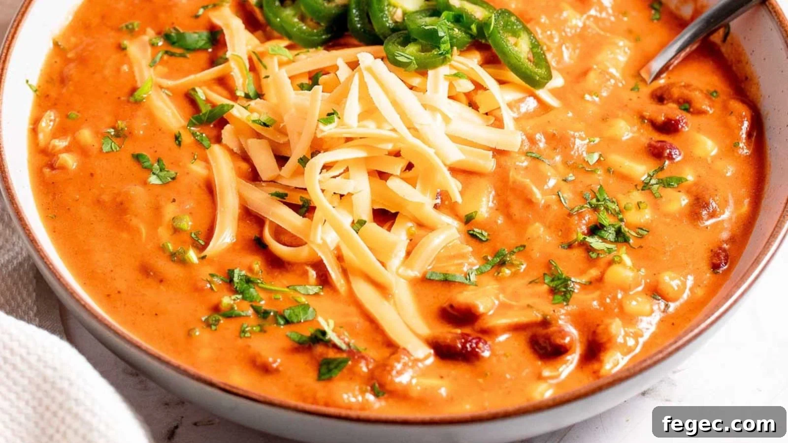 Chicken enchilada soup with shredded chicken and tortilla strips in creamy broth.