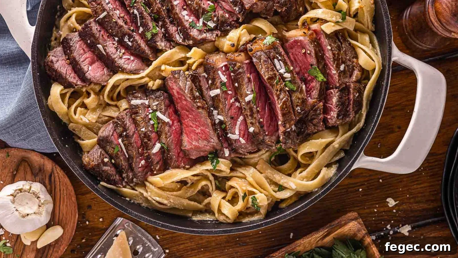 15 Flavor-Packed Skillet Recipes for Quick Cleanup 4 Creamy Alfredo noodles topped with sliced steak and cracked black pepper in a shallow bowl.