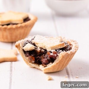Gluten free mince pies served in a star-shaped wooden box, on a white wooden background, with a small bowl of fruit mince and shaker of icing sugar.