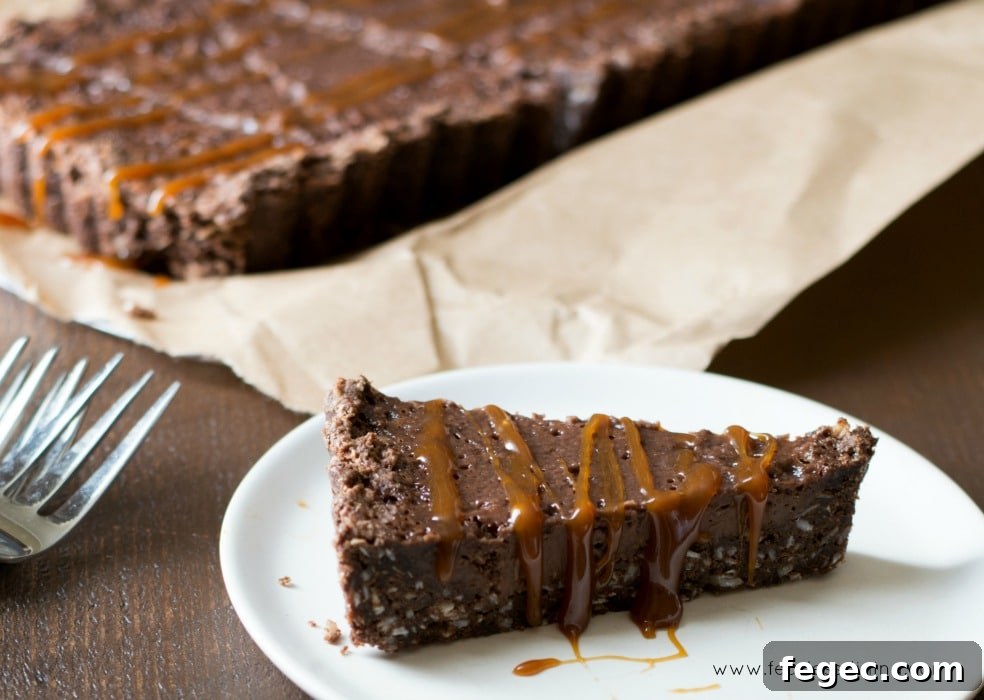 A slice of Chocolate Caramel Gluten Free Tart on a white plate with the tart in the background.