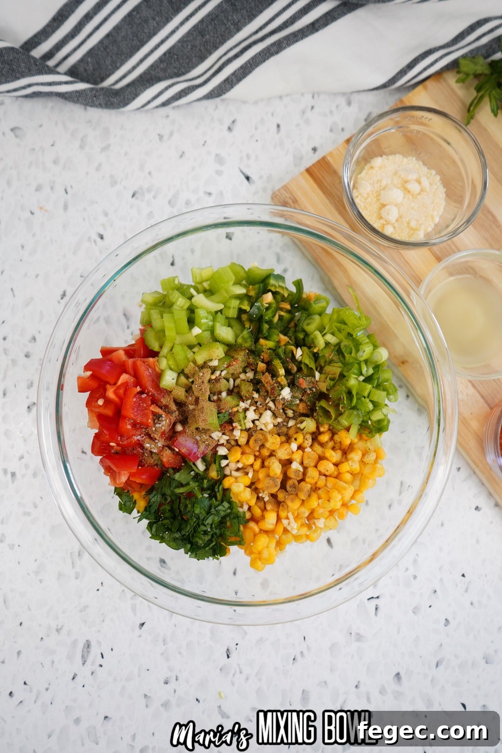 seasonings being added to the corn salad in a mixing bowl