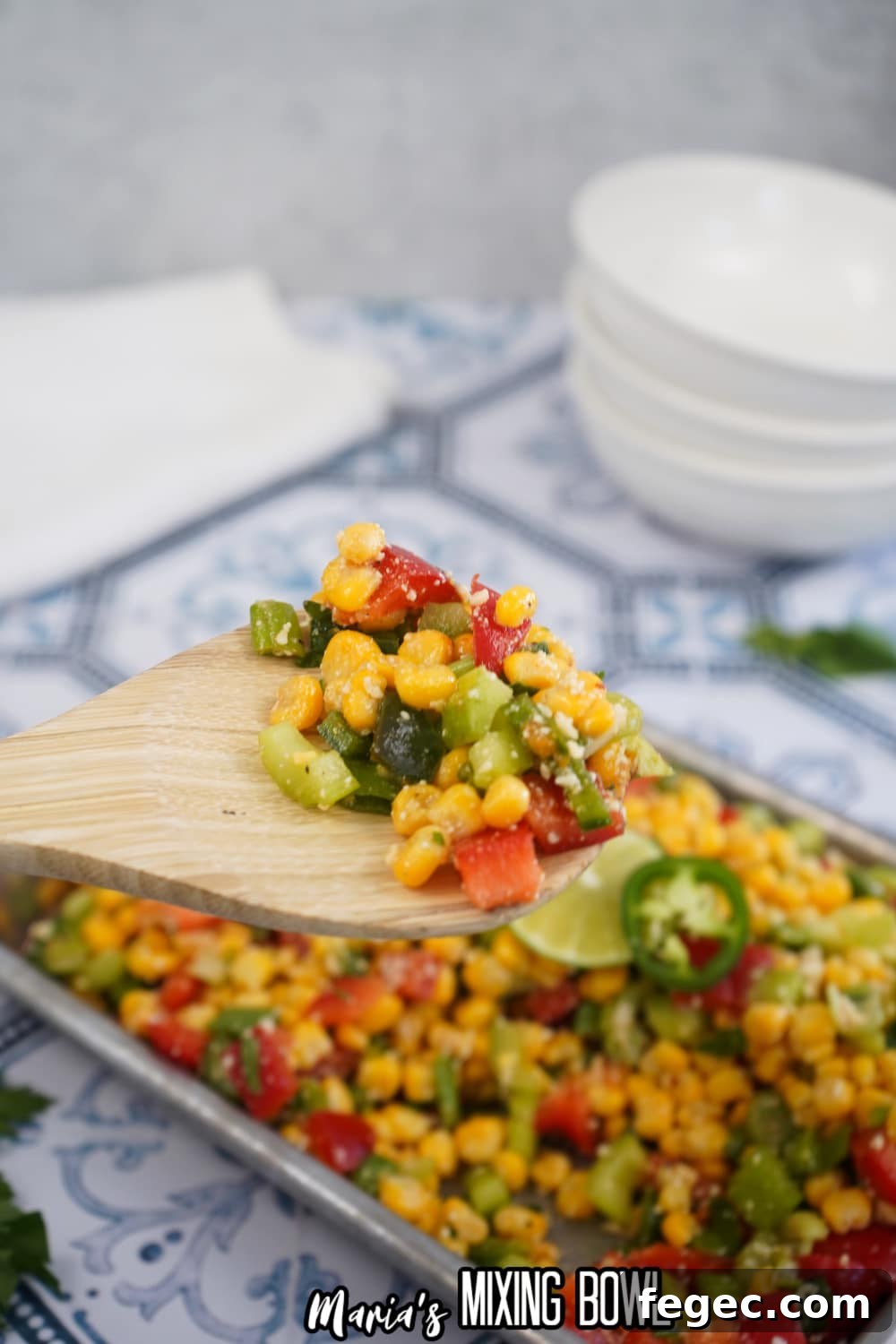 large bite of spicy corn salad on a wooden spoon held in the air