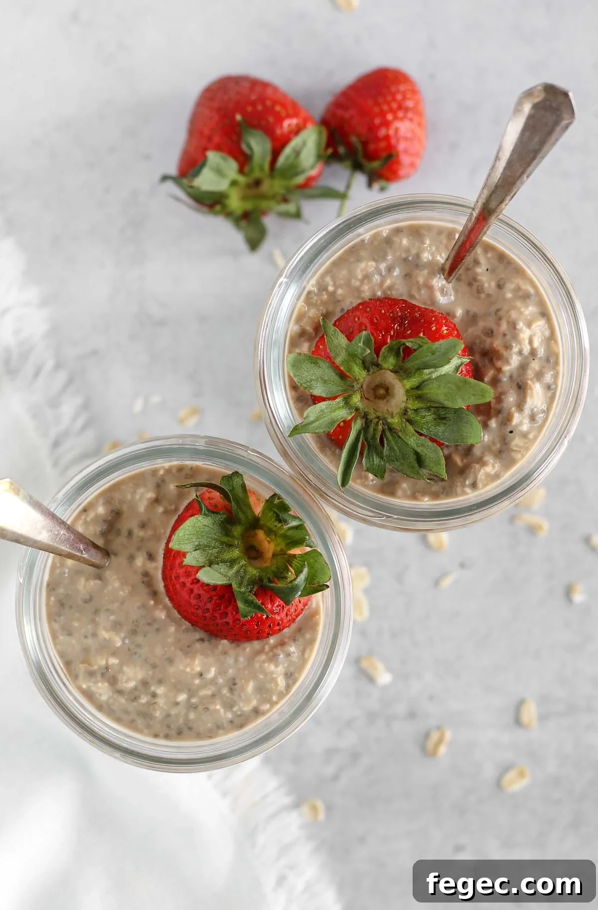 High-Protein Overnight Oats — 5-Ingredient Recipe 4 Overhead view of overnight oats topped with a strawberry in 2 mason jars.