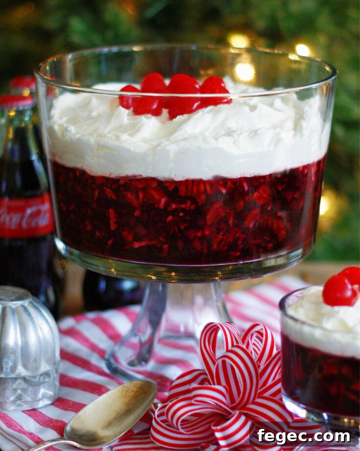 Coca cola jello salad in a trifle dish. Made with cherries, pineapple, coconut pecans, coca-cola and cherry gelatin.