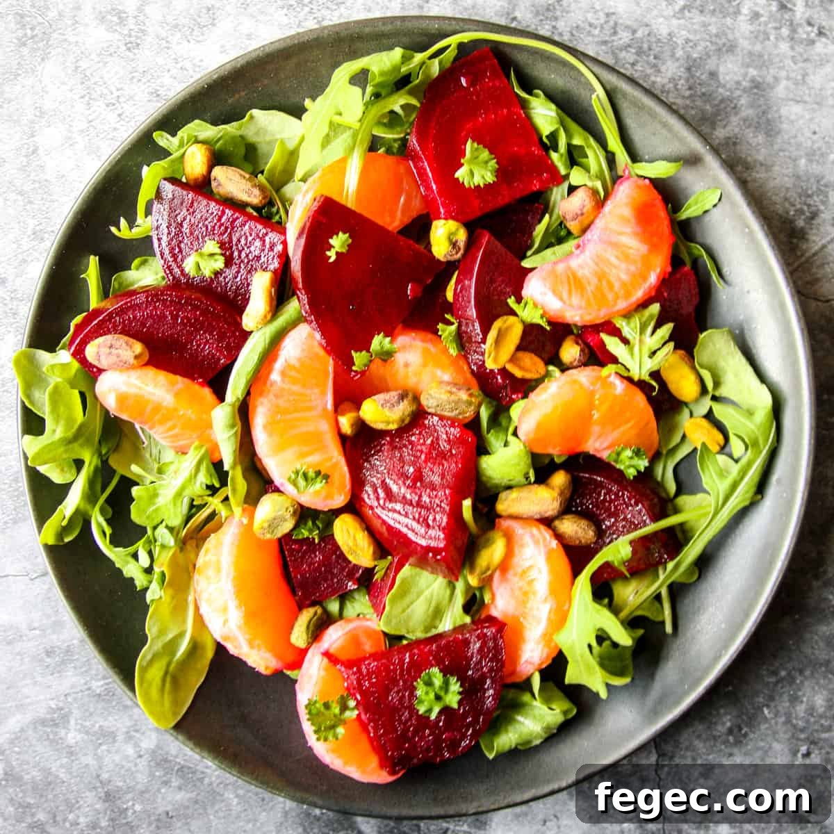 Roasted Beet and Orange Salad with Arugula and Goat Cheese 2 Colorful beet and orange salad on a black plate.