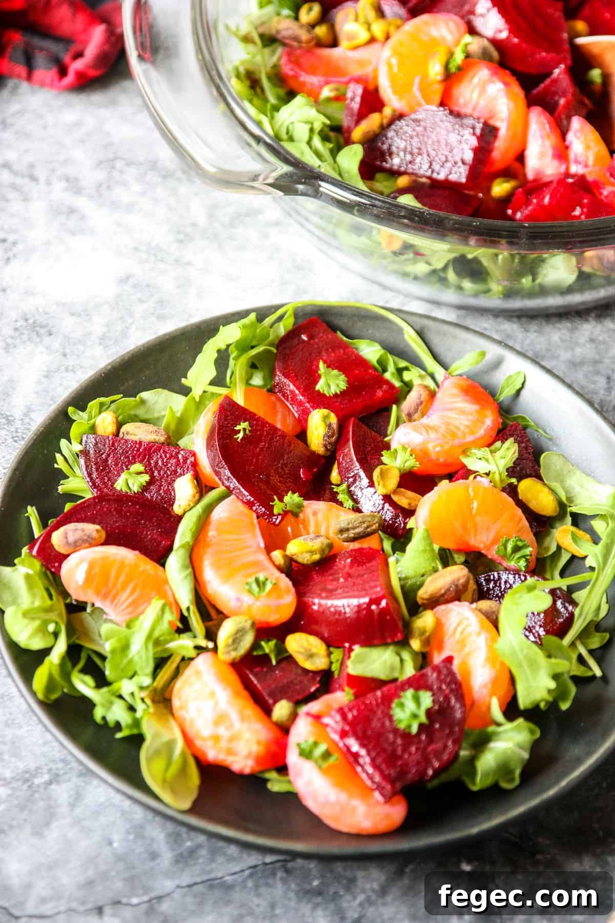 Roasted Beet and Orange Salad with Arugula and Goat Cheese 3 A serving of roasted beet and orange salad on a plate beside the serving bowl.