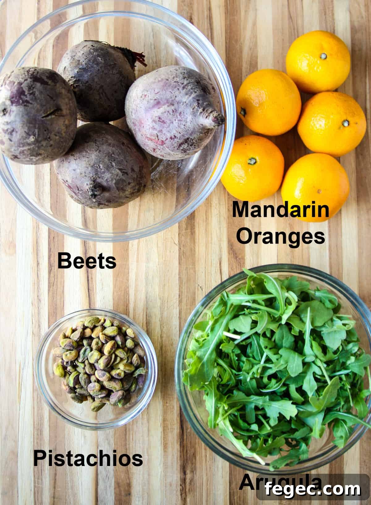 Roasted Beet and Orange Salad with Arugula and Goat Cheese 4 The ingredients for the salad in glass bowls on a wooden board.