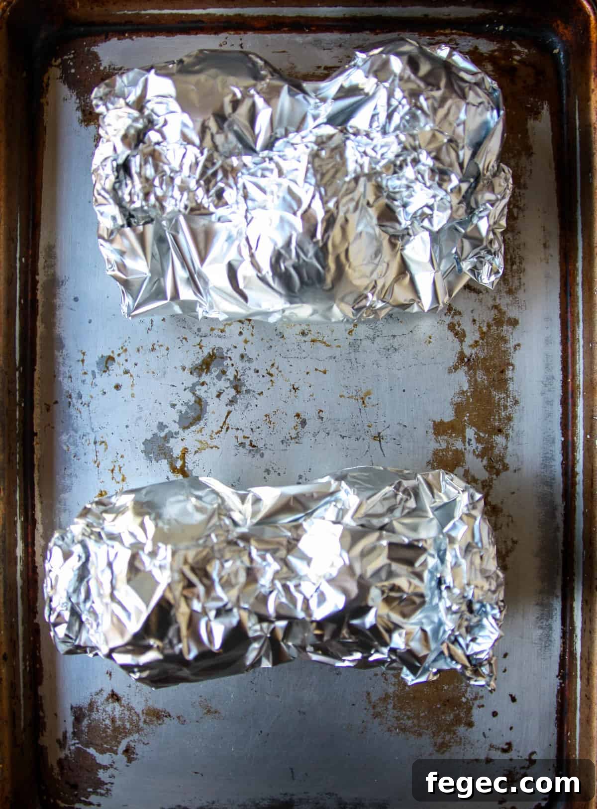 Roasted Beet and Orange Salad with Arugula and Goat Cheese 7 Two packages of beets wrapped in aluminum foil, on a baking sheet.