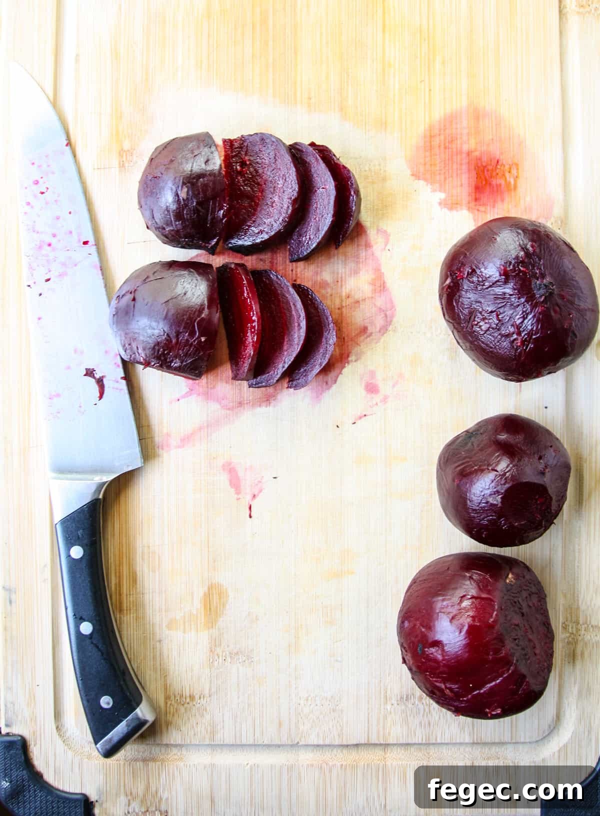 Roasted Beet and Orange Salad with Arugula and Goat Cheese 8 Cooked and peeled beets on a cutting board, sliced with a knife.