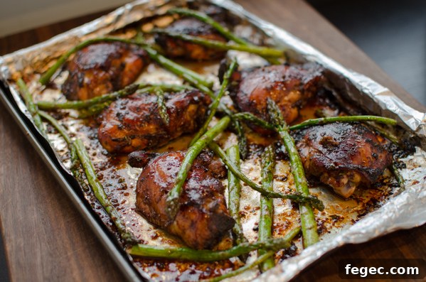 Soy Balsamic Chicken Thighs with asparagus on a baking sheet.