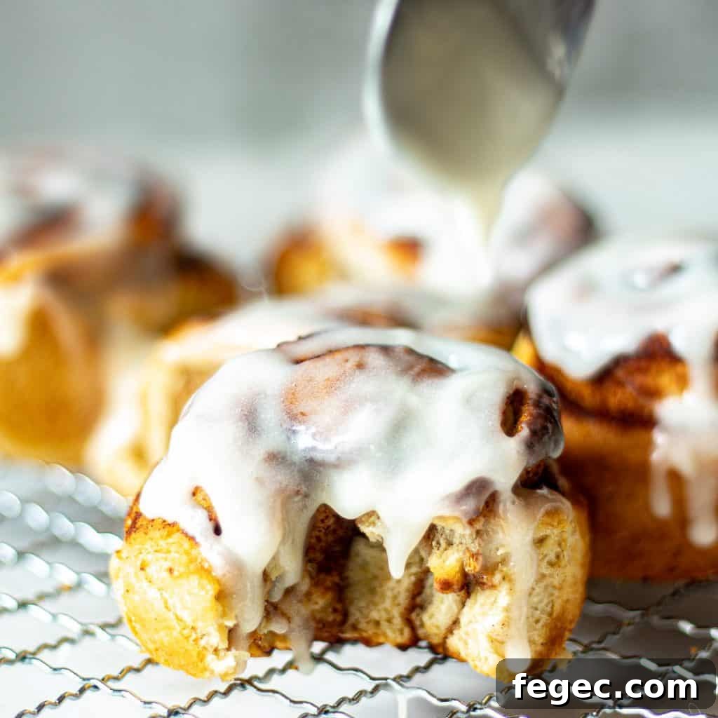 Closeup of air fryer cinnamon rolls with icing, one with a bite taken out of it