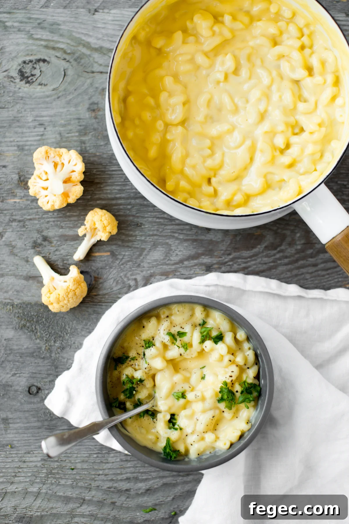 bowl of stovetop cauliflower mac and cheese with parsley and gray background