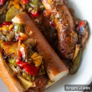 A plate of Italian sausage and peppers on a sub roll