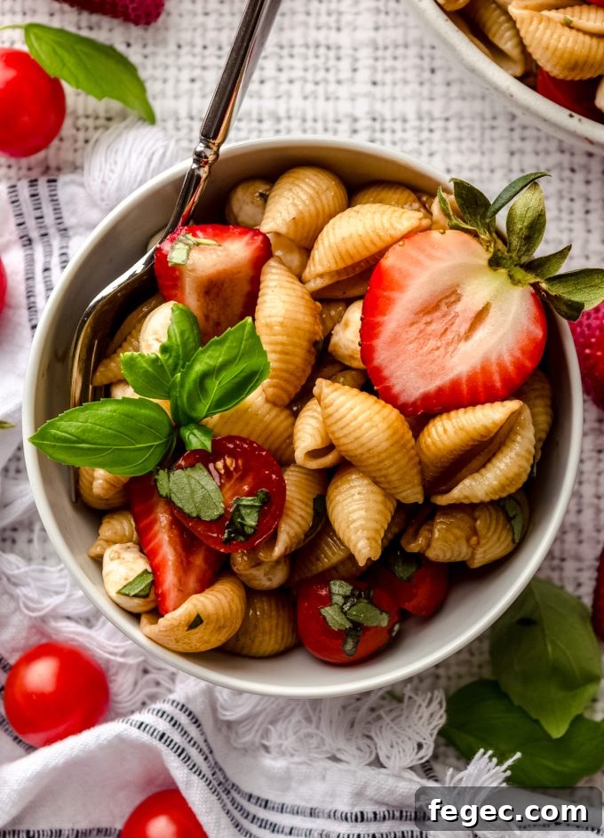 Aerial photo of strawberry caprese pasta salad in a bowl with a fork.