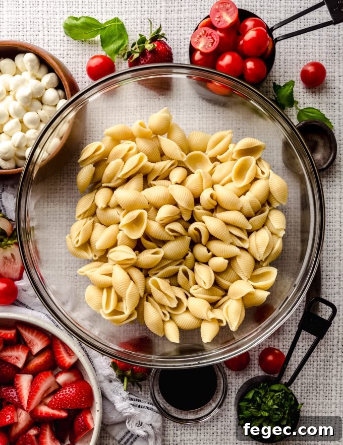 Aerial photo of a bowl of cooked pasta shells to make strawberry caprese pasta salad.