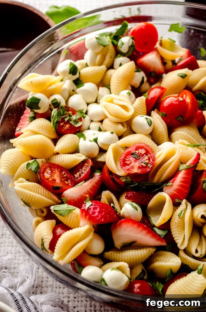 Closeup of strawberry caprese pasta salad in a bowl.