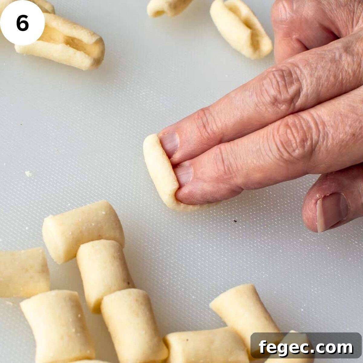 Two fingers rolling short pasta into cavatelli shapes.