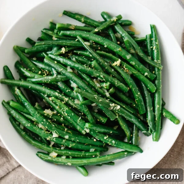 Green beans topped with lemon in a white bowl.