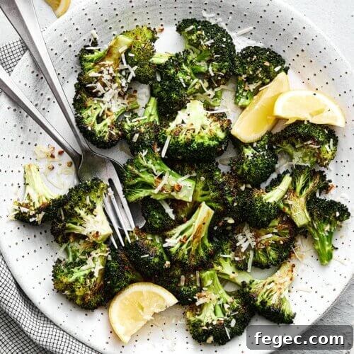 A white plate of roasted broccoli, parmesan, and garlic.