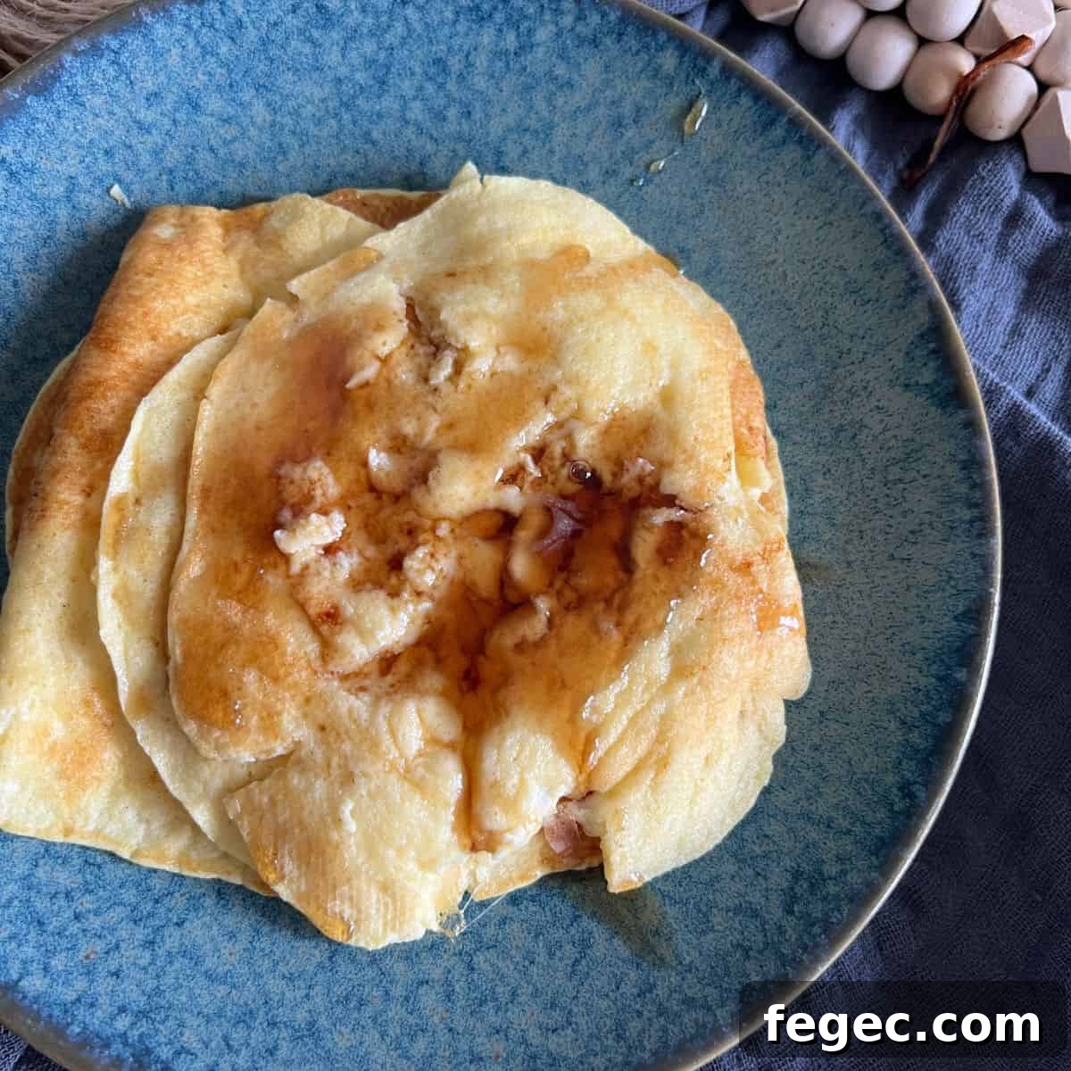 Cottage cheese pancakes topped with maple syrup on a blue plate.
