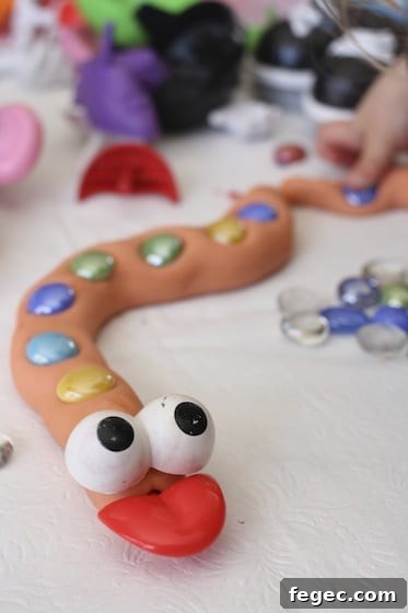 Homemade Playdough snake with potato head eyes and tongue, and glass beads along back.