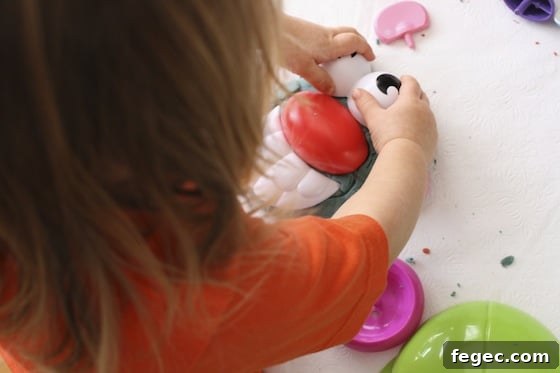 Adding Potato Head eyes to a play dough head.