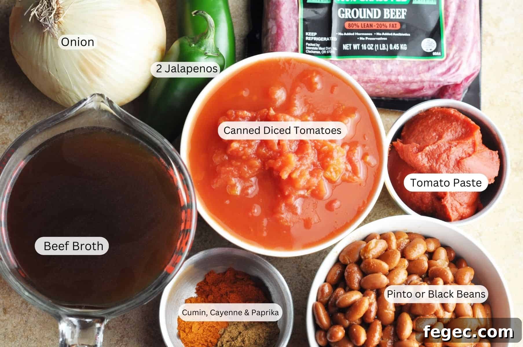 Ingredients for chili including onion, jalapenos, ground beef, beef broth, diced tomatoes, tomato paste, beans, and spices.