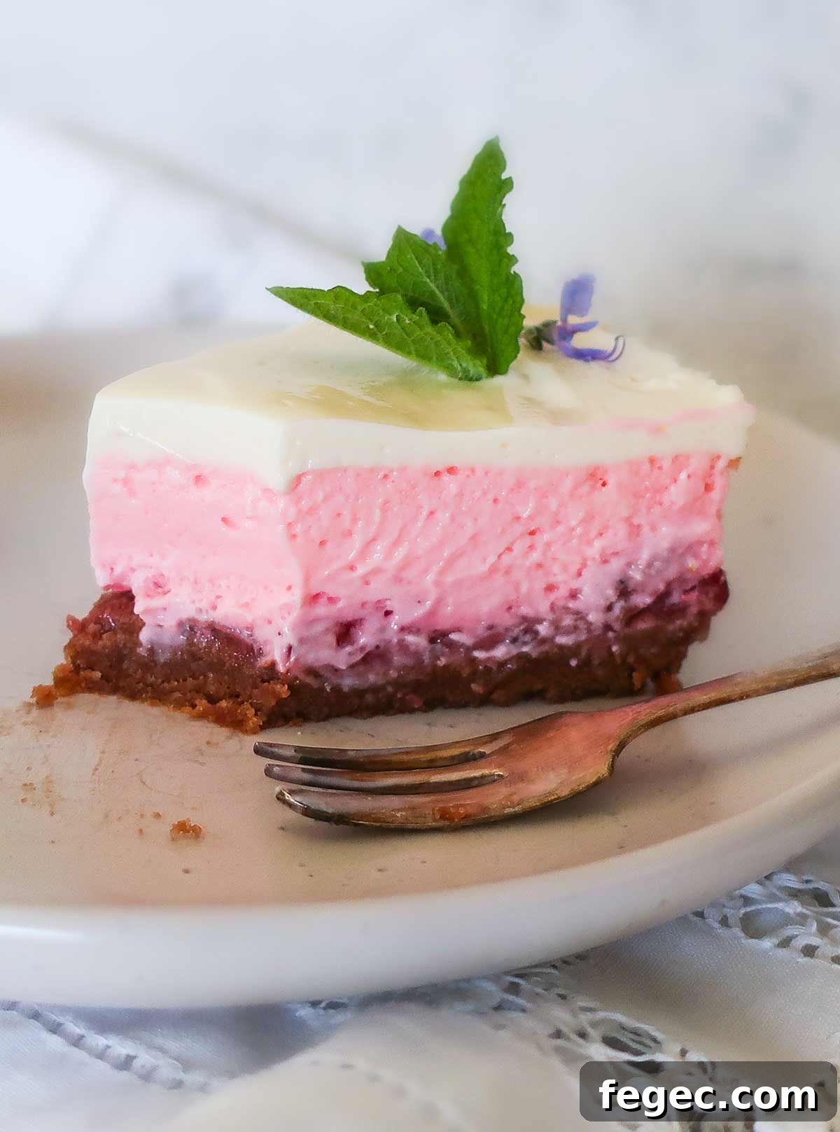close up of 4 layer strawberry cheesecake on a dessert plate