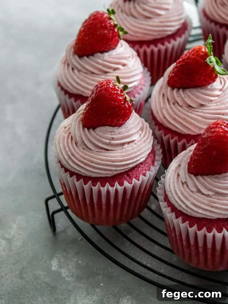 strawberry ermine frosting piped onto strawberry cupcakes on wire rack (1)