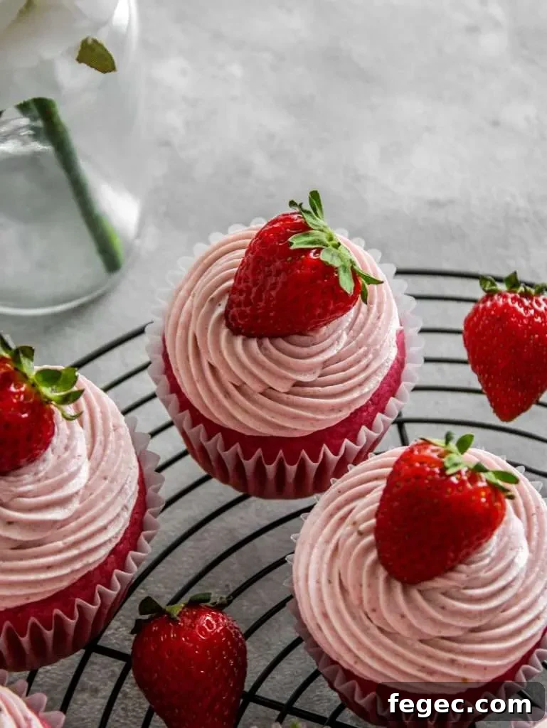 strawberry ermine frosting piped onto strawberry cupcakes on wire rack (4)
