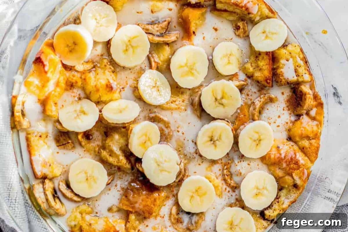freshly baked banana bread pudding topped with vanilla glaze in a baking dish.
