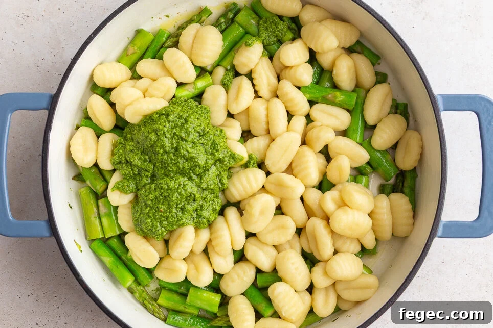 how to make pesto gnocchi: add pesto and cooked gnocchi to the pan with the sauteed asparagus